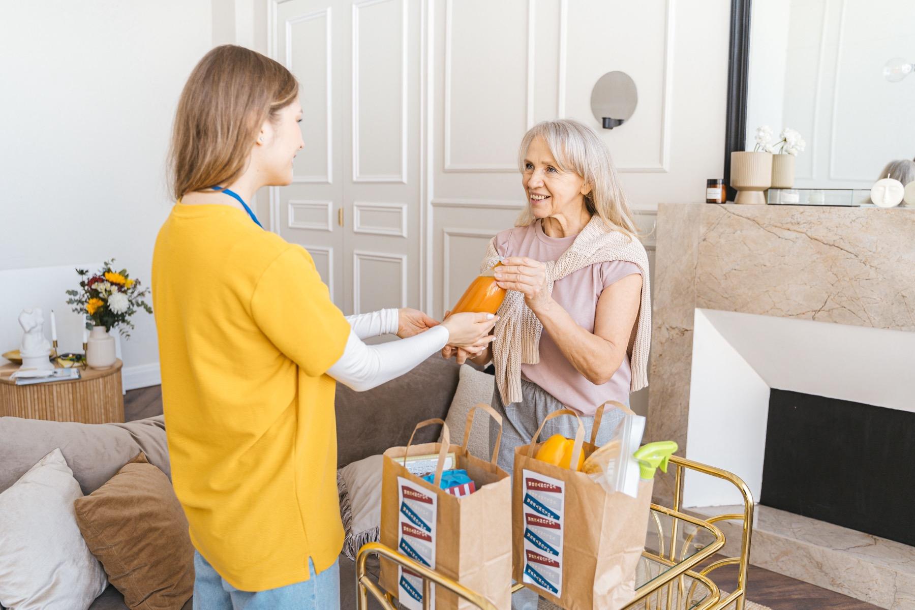 Caregiver helping an older adult with daily supplies in a bright home